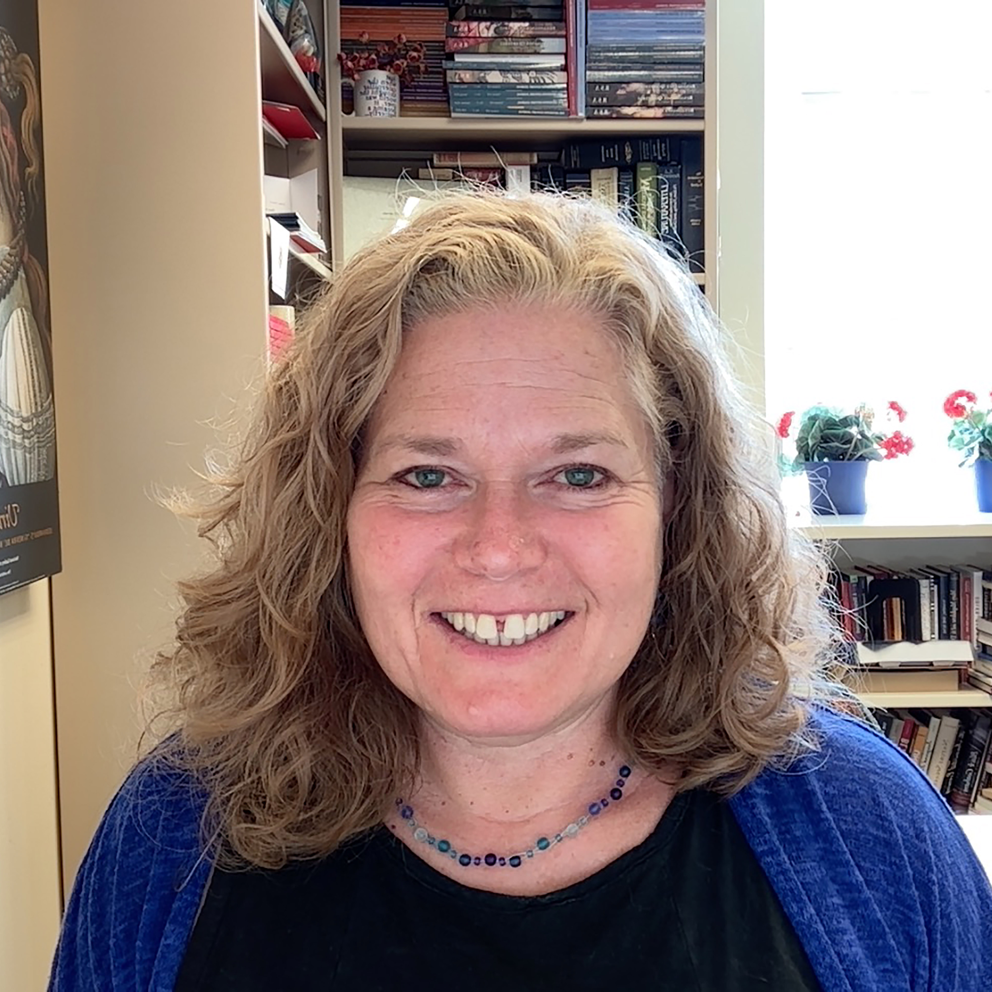 Smiling woman seated in front of bookcases and window